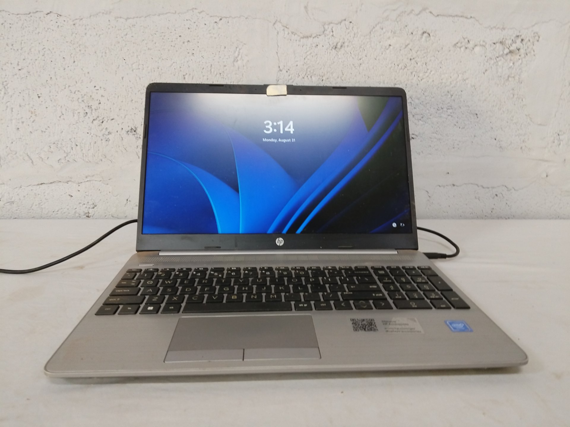 HP 15-class laptop — powers on, OEM charger included, battery holds charge, logged-in (needs credentials) — visible wear, webcam taped