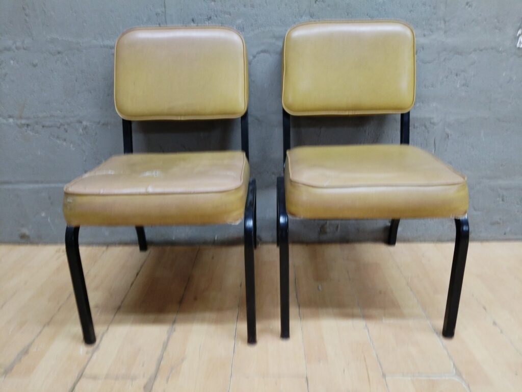 Pair of metal-frame vinyl-upholstered chairs – tan/yellow, stable frames, worn seats