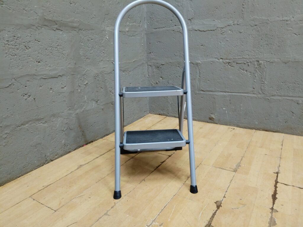 2-step folding step ladder — silver metal frame, rubber treads & feet, folds and locks (EN131 label)