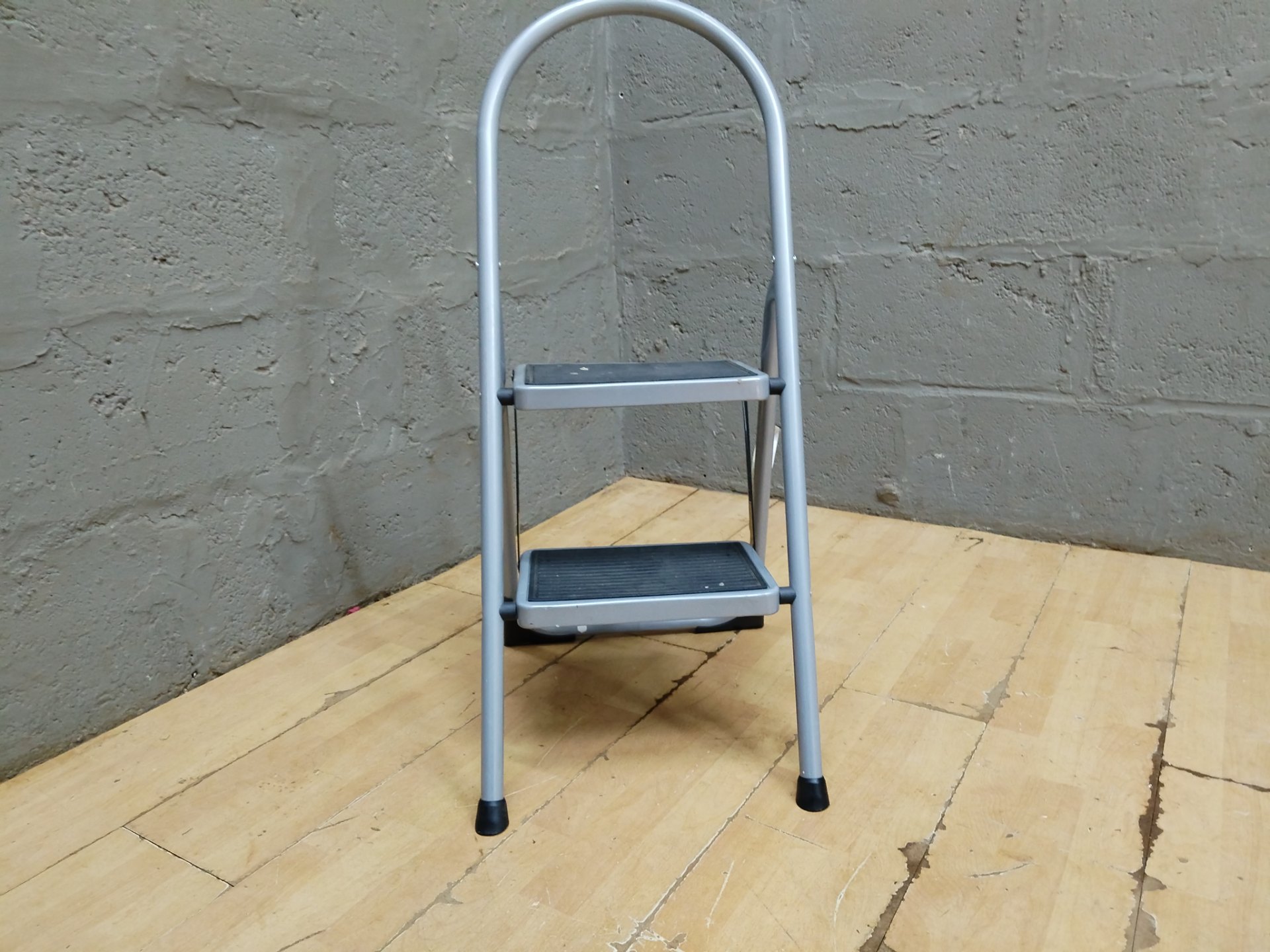 2-step folding step ladder — silver metal frame, rubber treads & feet, folds and locks (EN131 label)