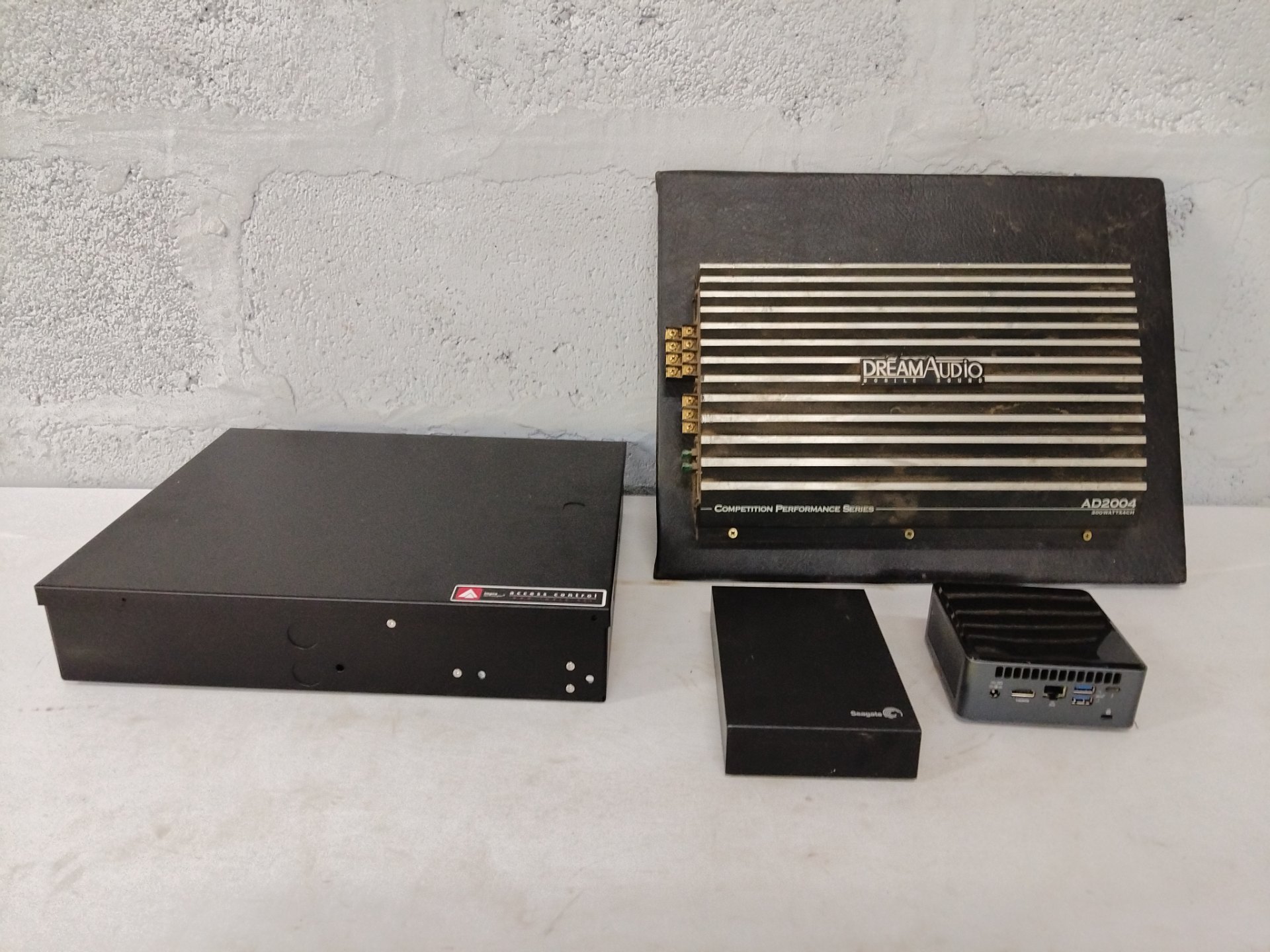 Mixed electronics lot: DreamAudio AD2004 car amplifier + Impro access-control enclosure (cluster controller + PSU) + Seagate external HDD enclosure + mini‑PC
