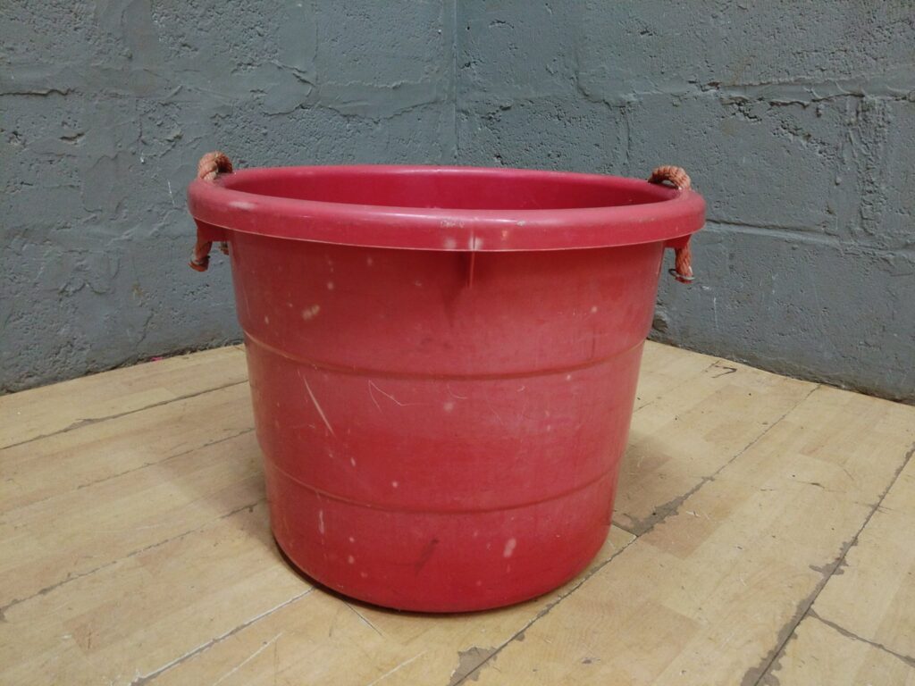 Large red plastic utility tub with rope handles — used, paint-marked