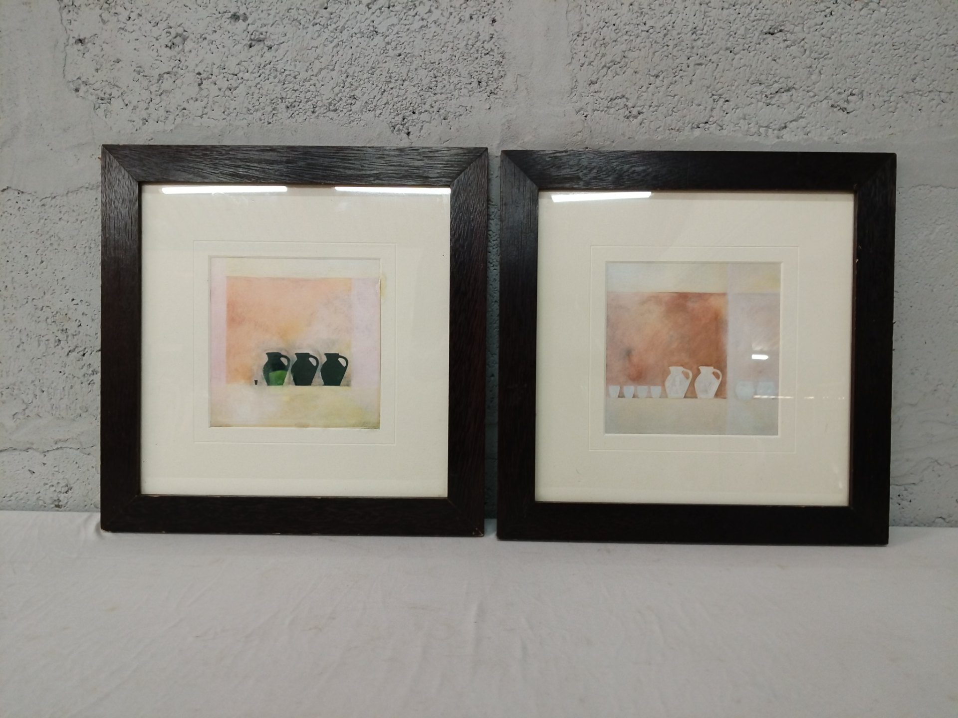 Pair of framed small jug prints — dark wood frames, glass intact, mats yellowed (35 x 35 cm each)