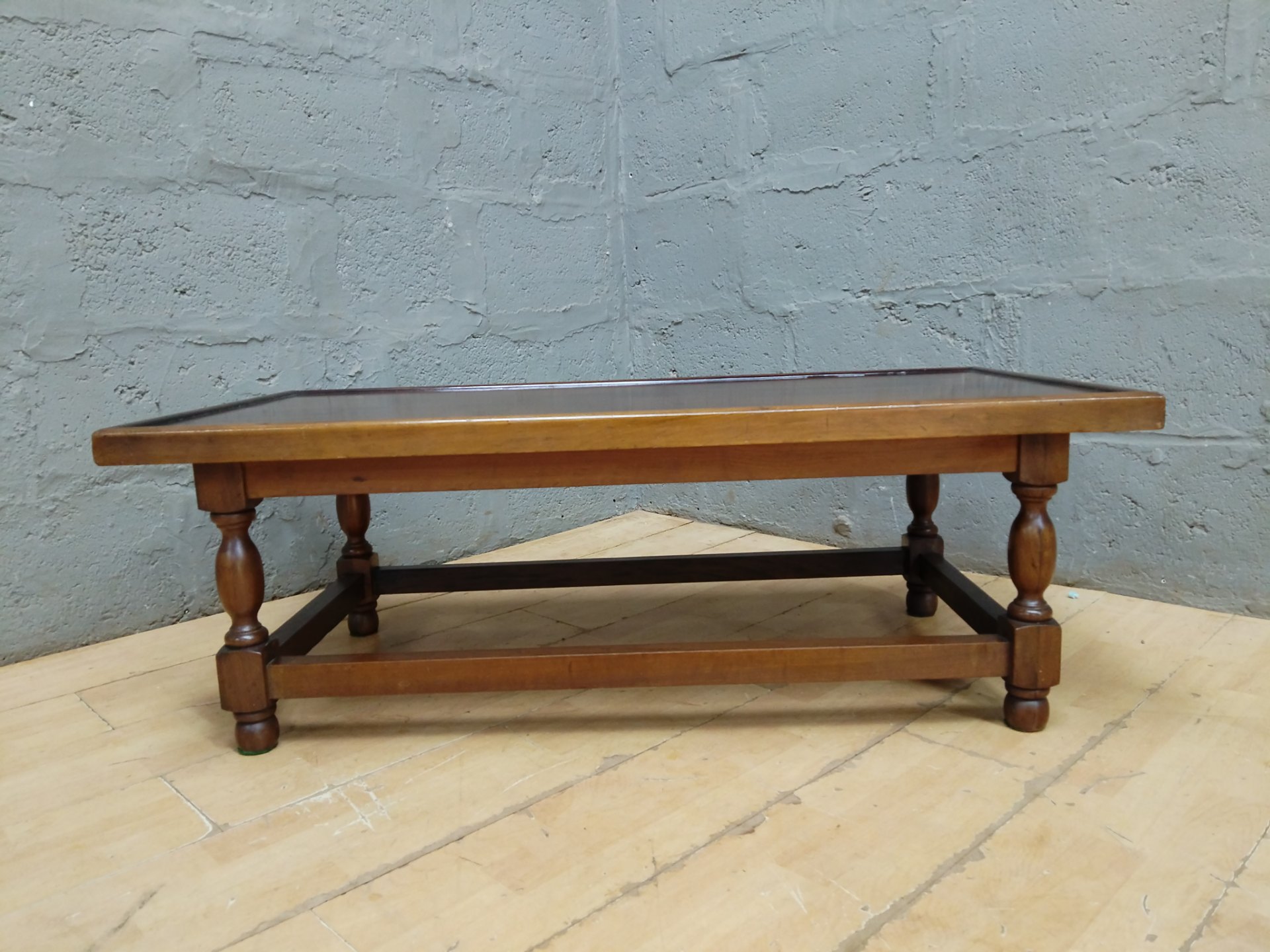 Low rectangular wooden coffee table with turned legs and stretcher (120 x 60 x 42 cm)