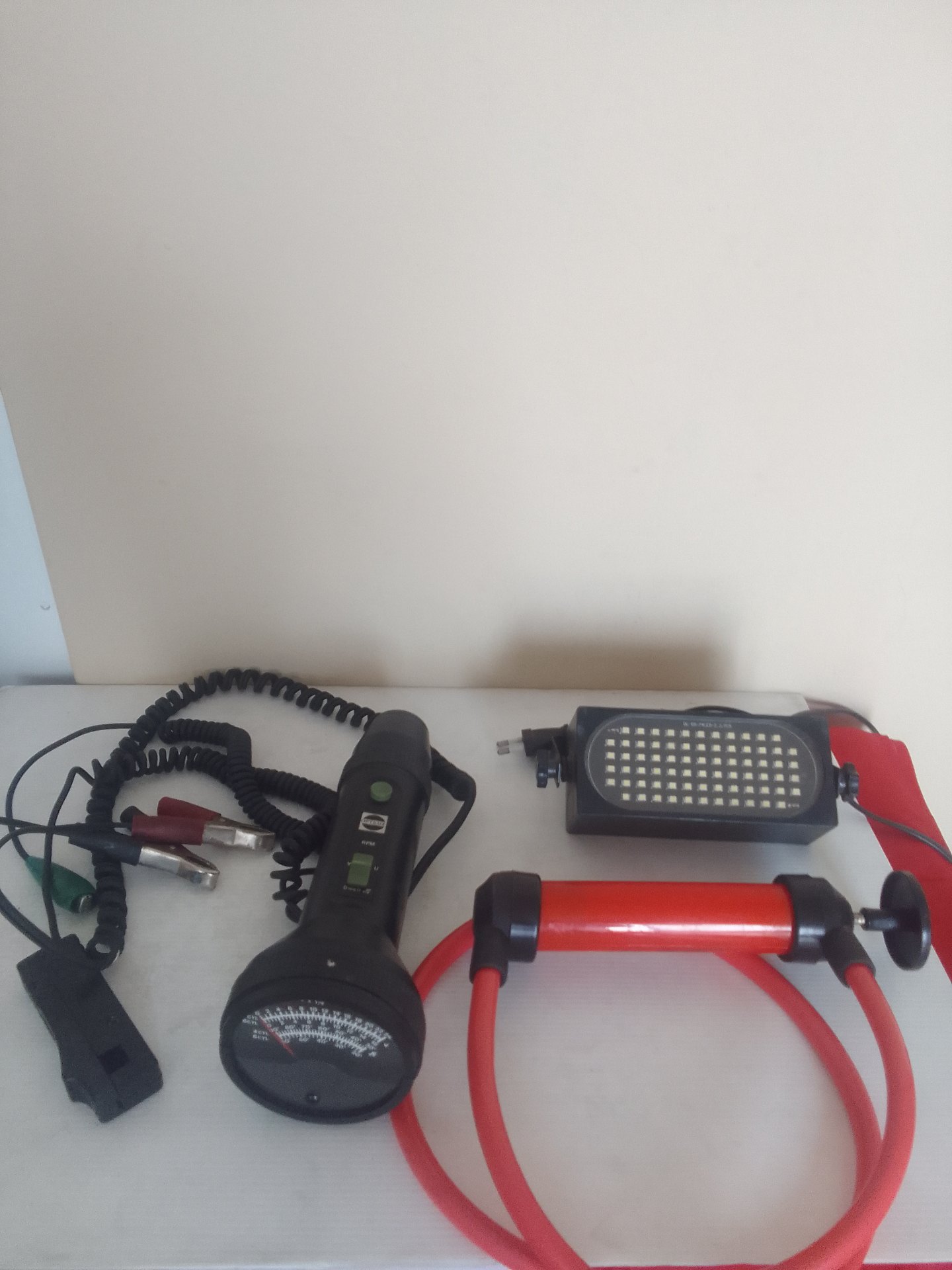 Mixed lot: 3 automotive/portable electrical items — analogue gauge with leads, LED worklight, red hand pump with hoses