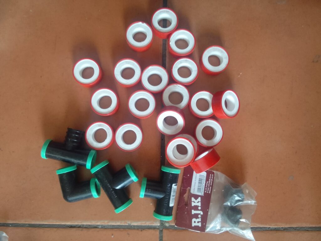 Mixed plumbing parts lot — red PTFE thread seal tape rolls + RJ.K plastic pipe connectors (mostly new)