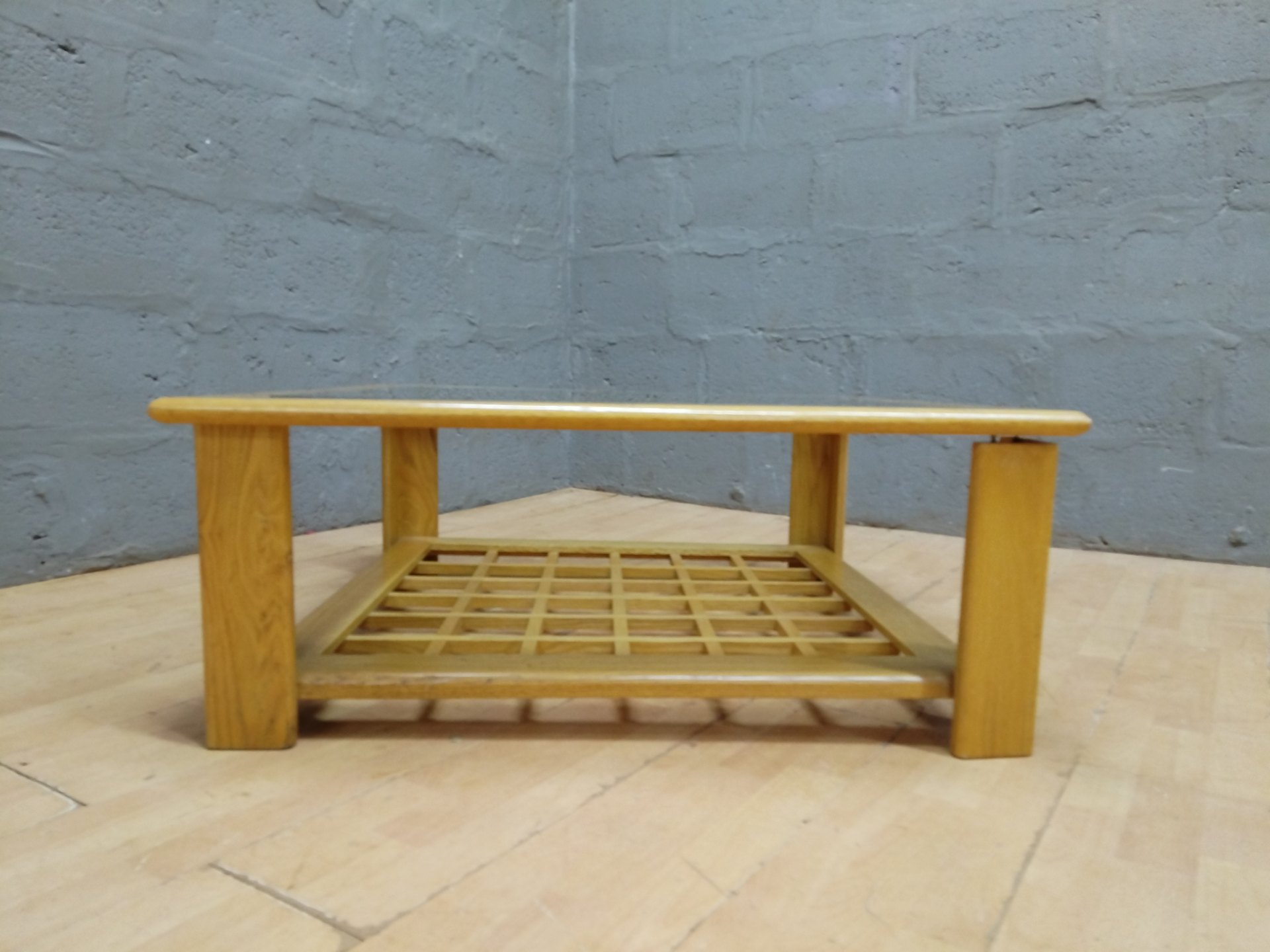 Square wooden coffee table with inset glass top and lower lattice shelf