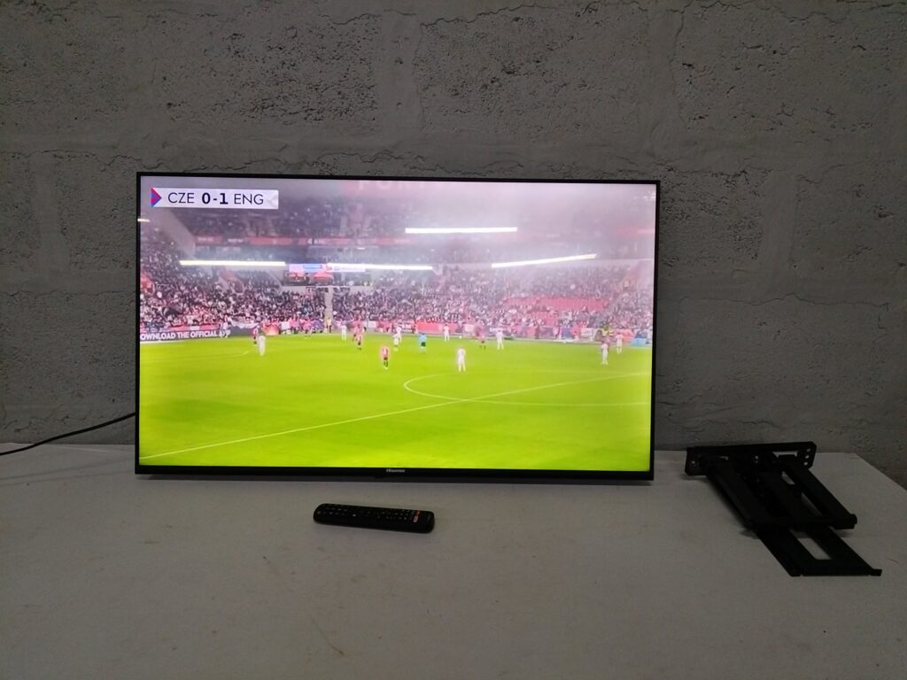 Hisense flat‑screen TV (96 x 56 cm) — powers on, remote & wall‑mount included, minor bezel chip