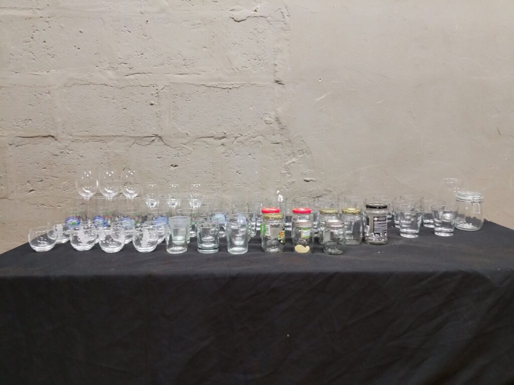 Mixed lot of 40 clear glassware & small jars — tumblers, shot glasses, stemmed wine glasses