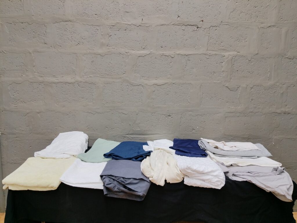 Bulk lot: 15 assorted bed linens, sheets, pillowcases and towels — mixed colours, good used condition