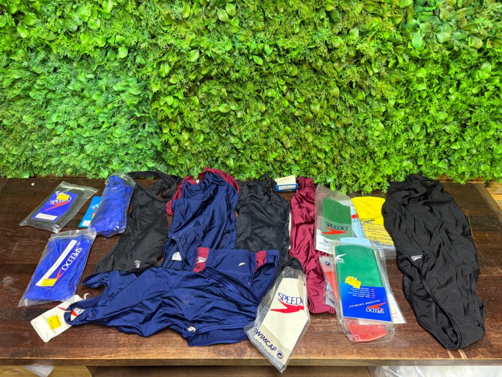 Mixed lot Speedo swimwear & accessories — assorted one-piece swimsuits with sealed Speedo caps