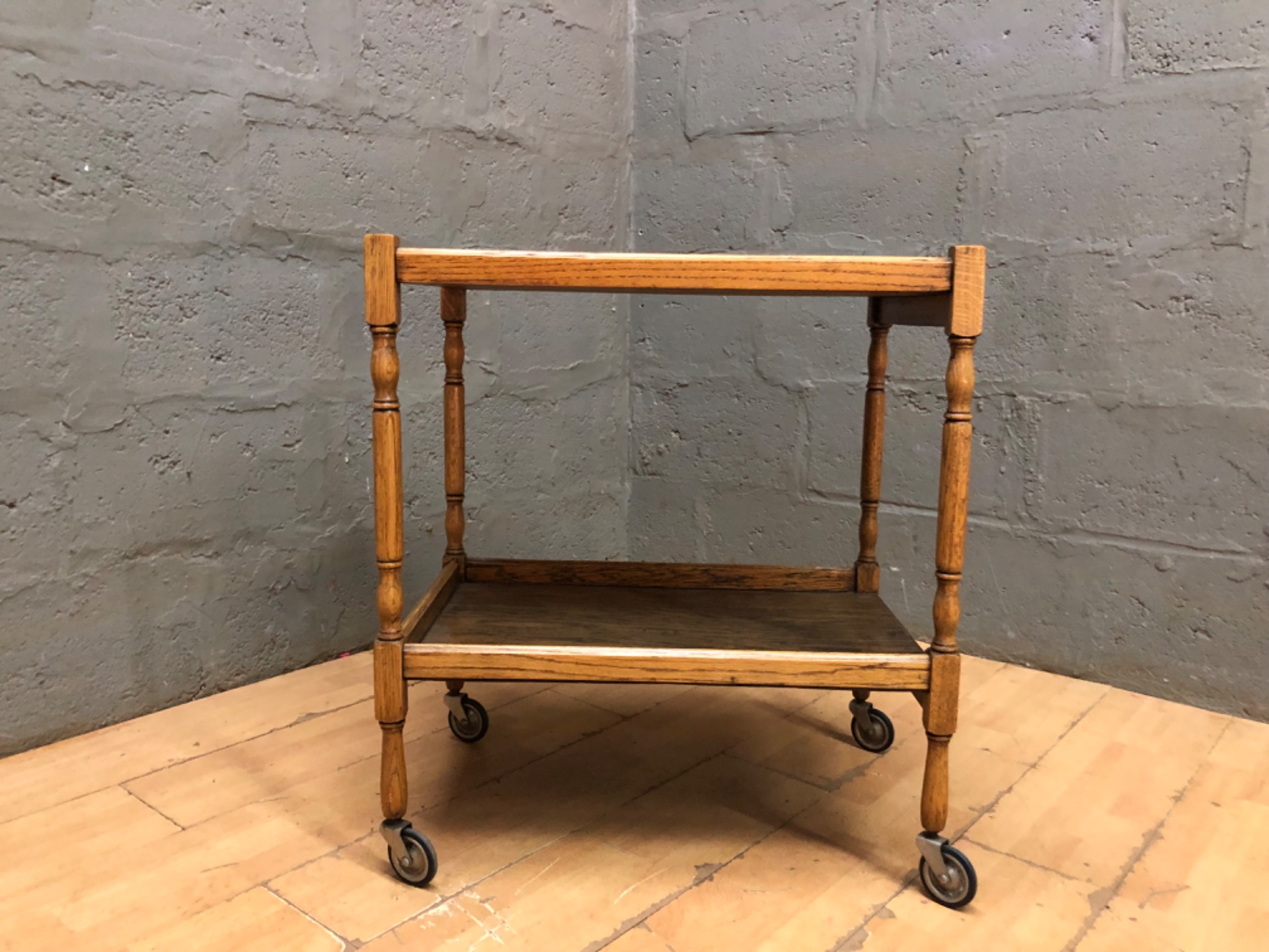 Two-tier wooden trolley on castors — oak-colour finish, turned legs (45 × 68 × 77 cm)