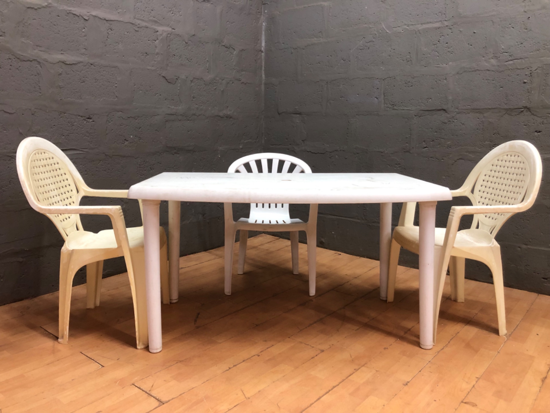 Used plastic outdoor table (131 x 82 x 71 cm) with 3 plastic chairs – heavy cosmetic wear, sold as-is