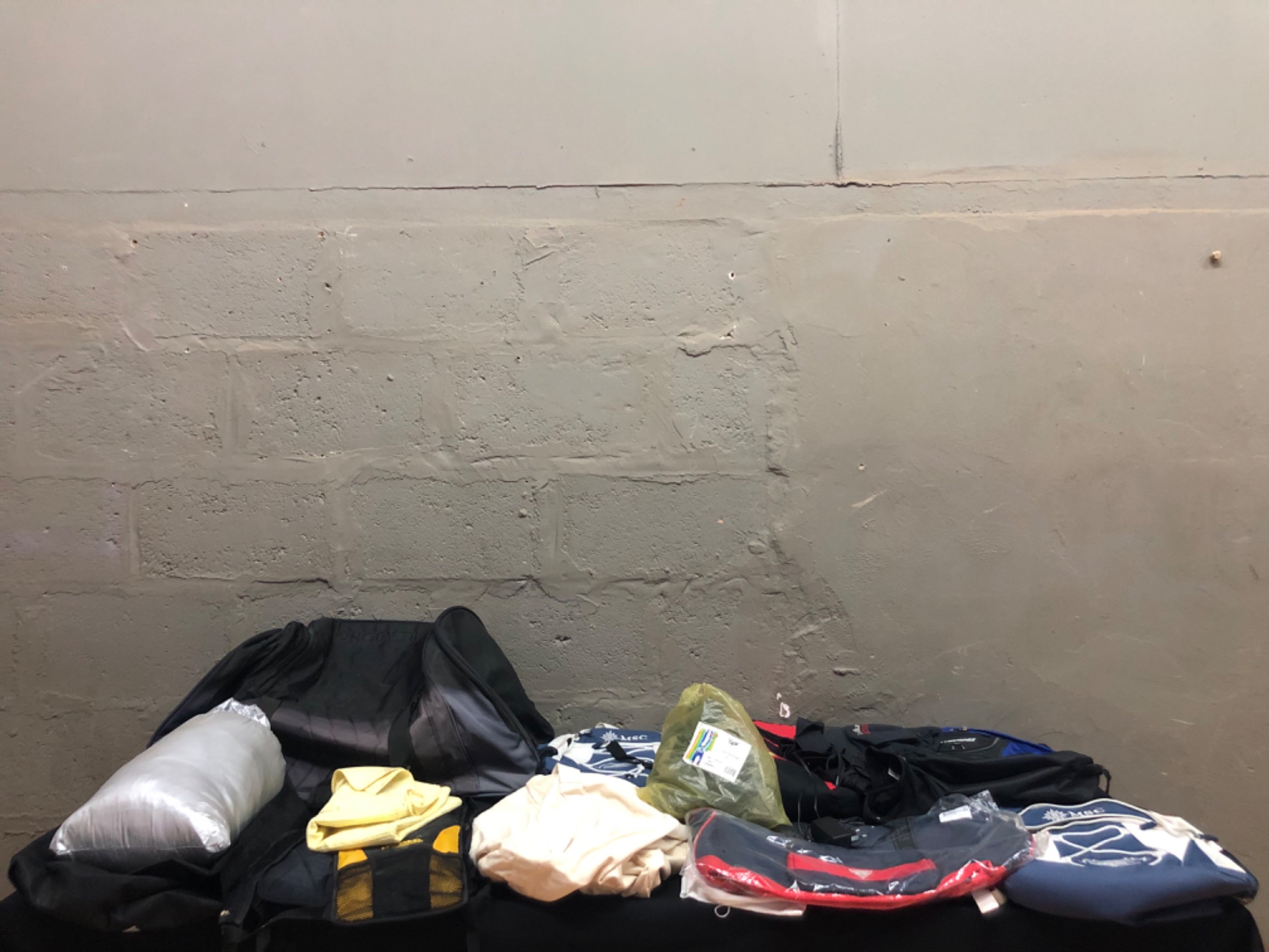 Mixed lot — 14 backpacks, bags, clothing & accessories (logos visible: MSC, Billabong, Ferrari, Guess)