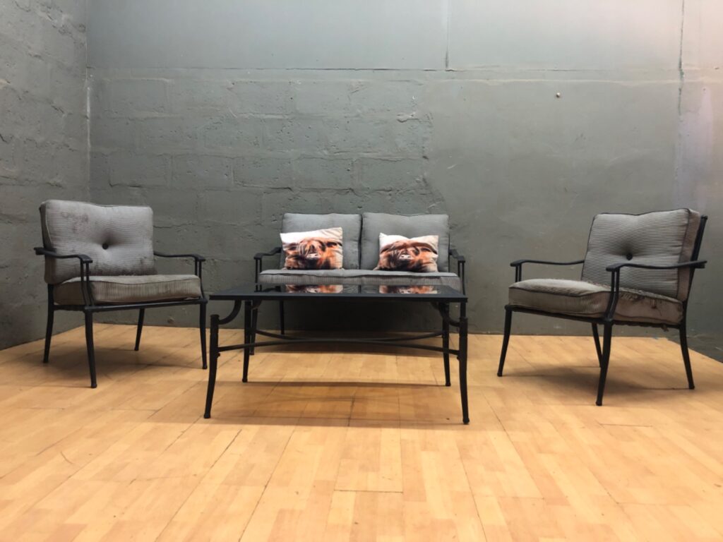 Outdoor patio furniture set — 2 armchairs, 2-seat loveseat, glass-top coffee table & 2 decorative cushions (frames intact; cushions heavily torn)