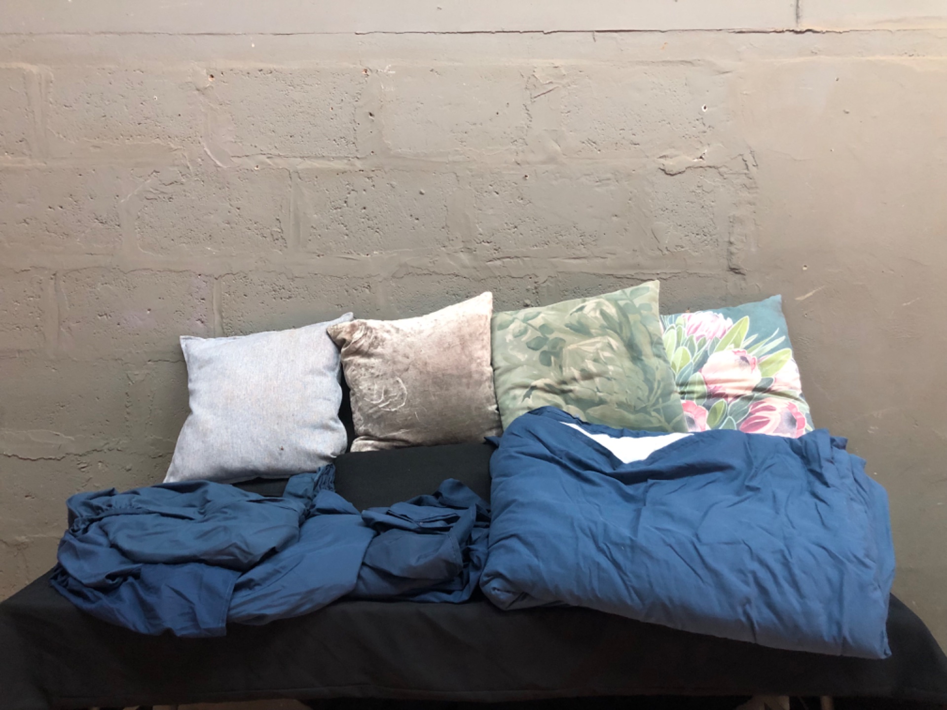 Used compact sofa with decorative cushions and blue duvet (duvet inner included) – visible wear & stains