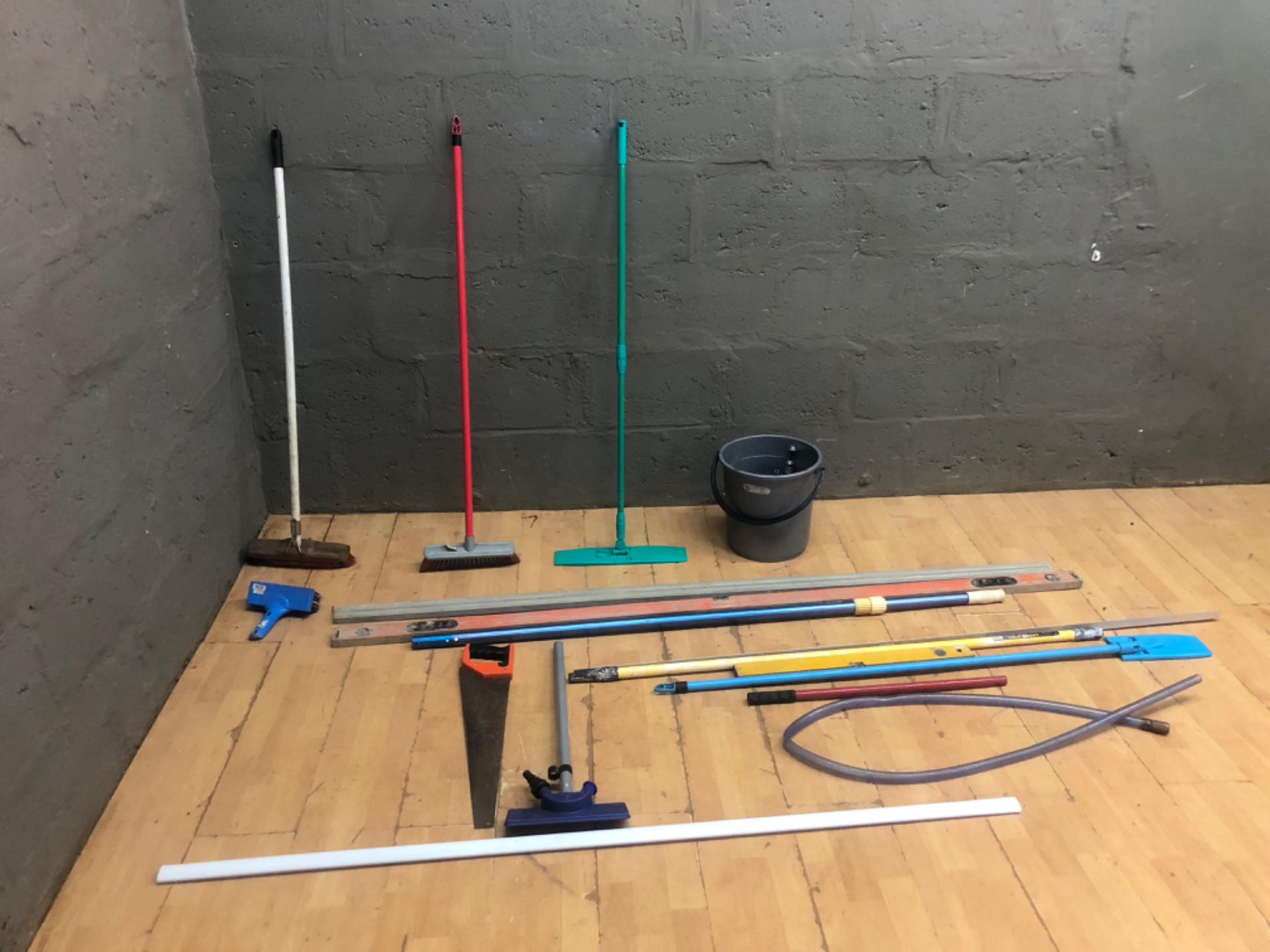 Lot: 17x Used Cleaning Tools & Pole Implements — Brooms, Squeegees, Bucket, Levels, Hose, Hand Saw (blade exposed)