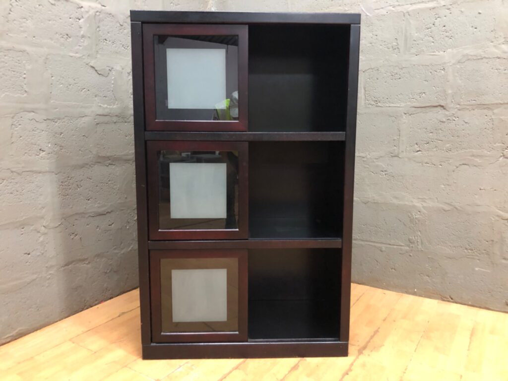 Tall narrow 3-cubby shelving unit with three sliding glass-front doors — dark finish, glass intact
