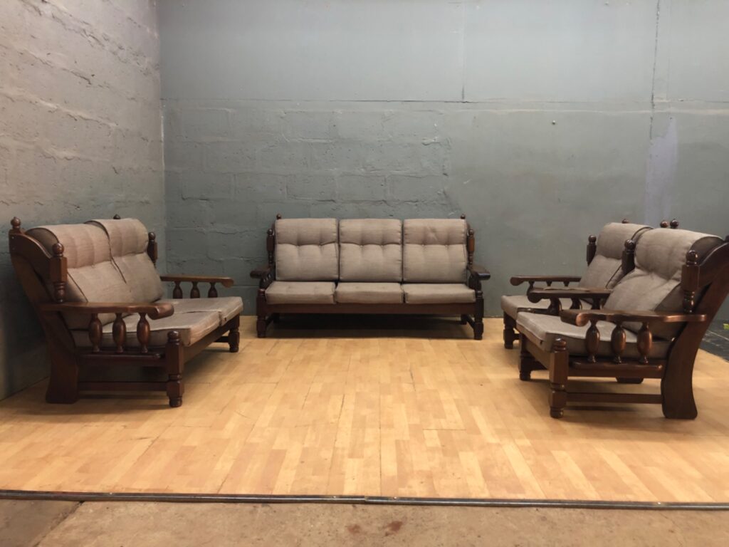 4‑piece solid timber living room suite — 3‑seater + 2 armchairs + matching piece (beige tufted cushions, visible wear)