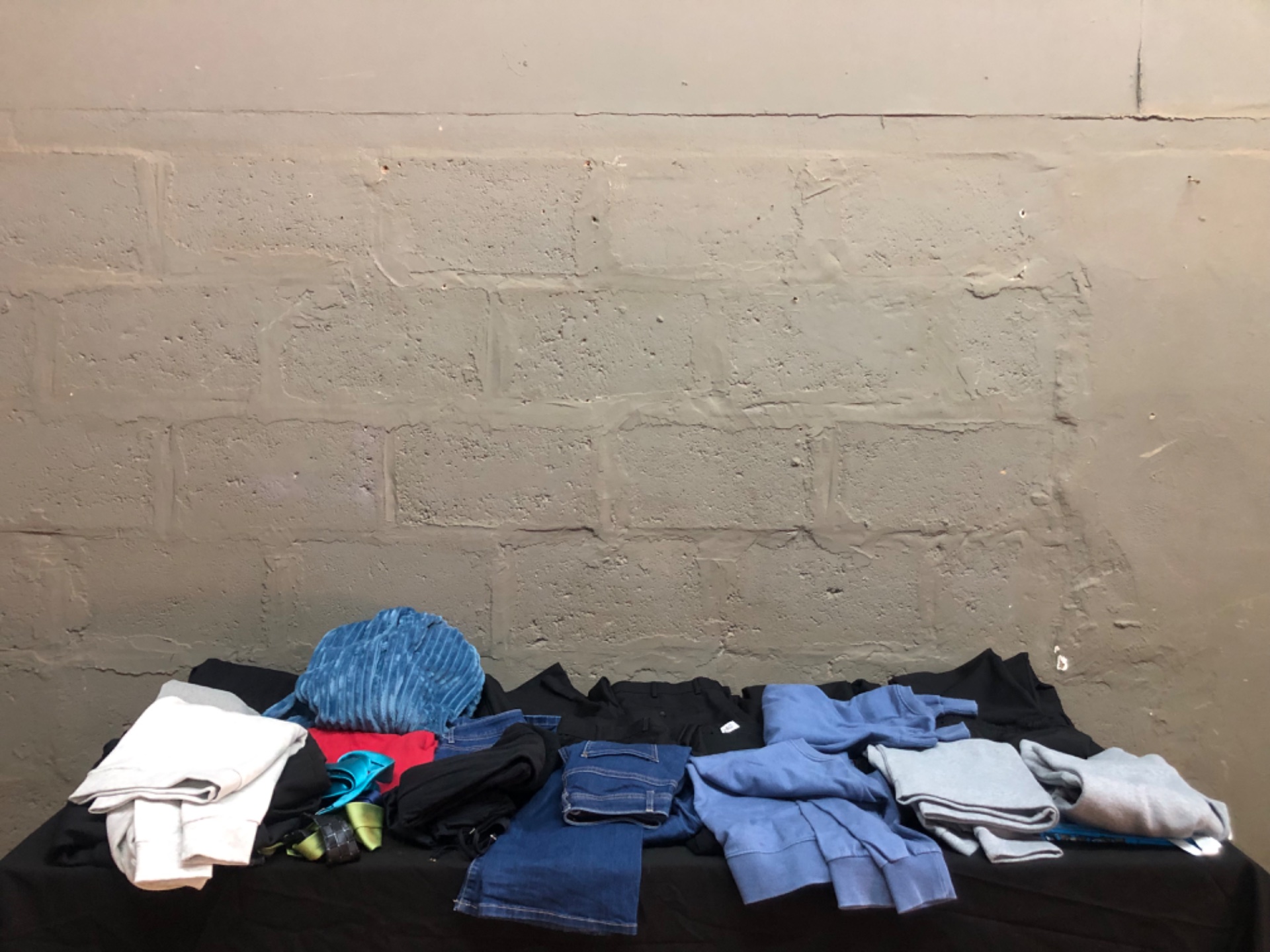 Mixed clothing lot — folded jeans, black trousers, sweatshirts & ties (Woolworths tag visible)