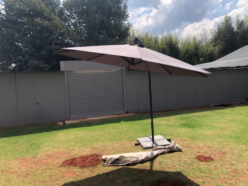 Patio umbrella with 180 cm canopy and weighted cross base — cracked hub & one broken slab