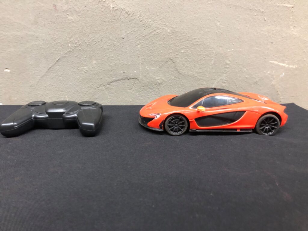 McLaren-branded orange RC car with remote — warehouse-tested, batteries included, heavy cosmetic wear