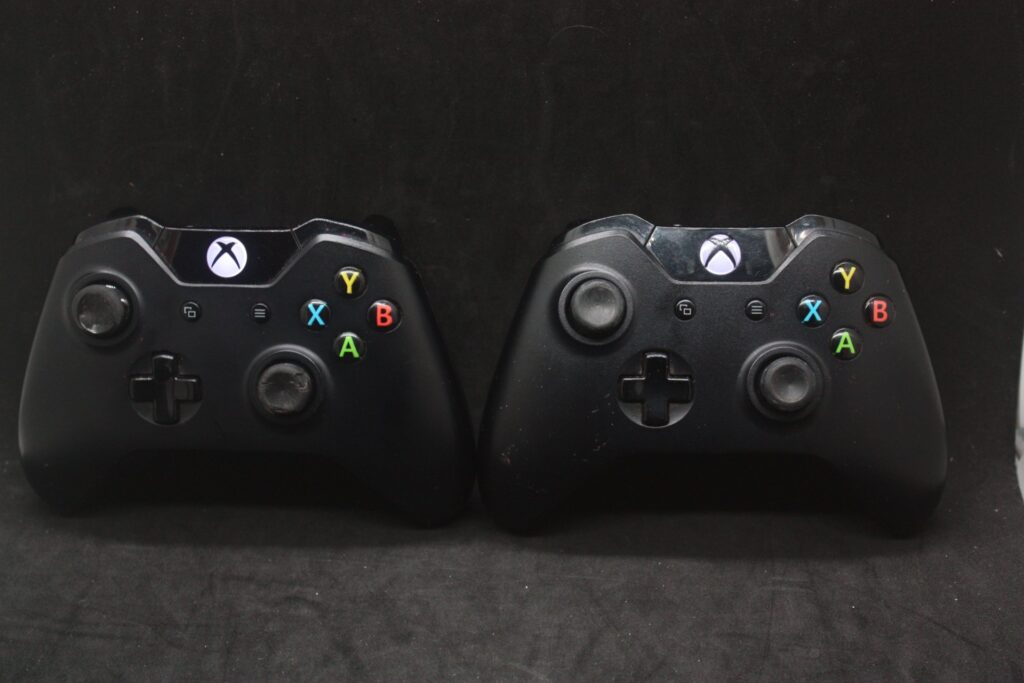 Pair of official Xbox One wireless controllers — powers on, sold as‑is, heavy thumbstick wear