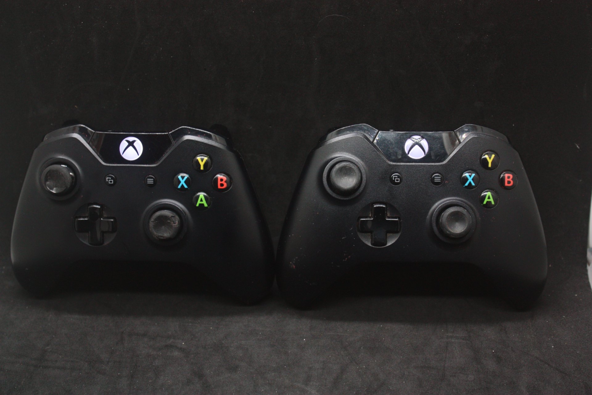 Pair of official Xbox One wireless controllers — powers on, sold as‑is, heavy thumbstick wear