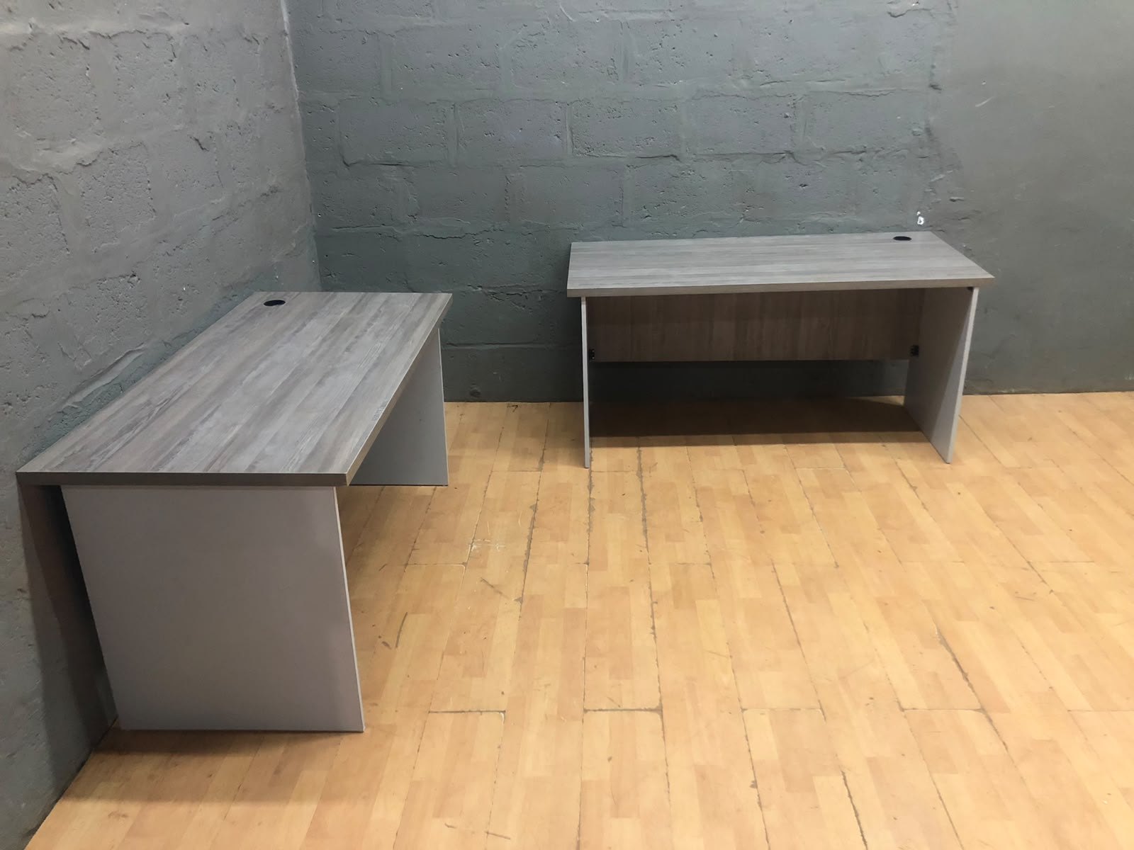 Lot of 2 Laminate Office Desks — Grey woodgrain tops, cable grommets, modesty panels (fair condition)