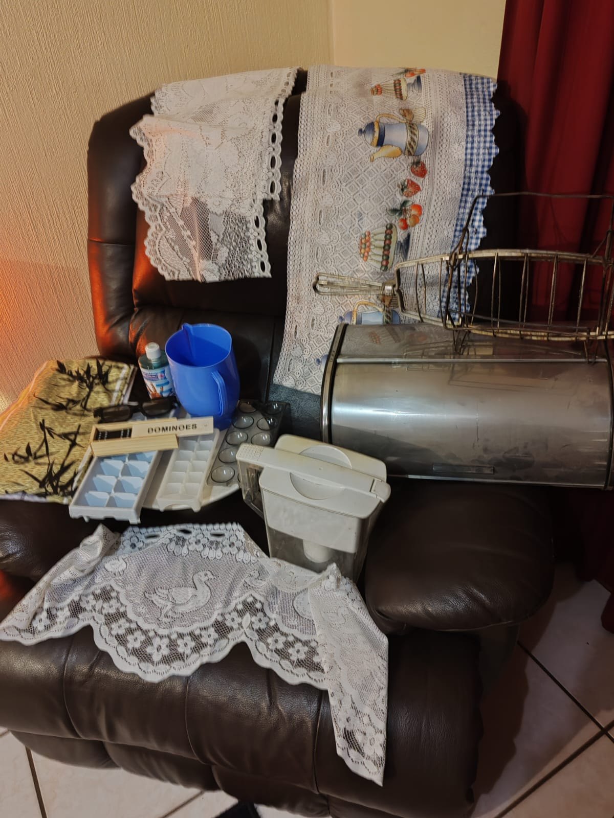 Mixed kitchen lot — stainless roll-top bread/bin with removable racks, lace curtains, linens and assorted kitchenware