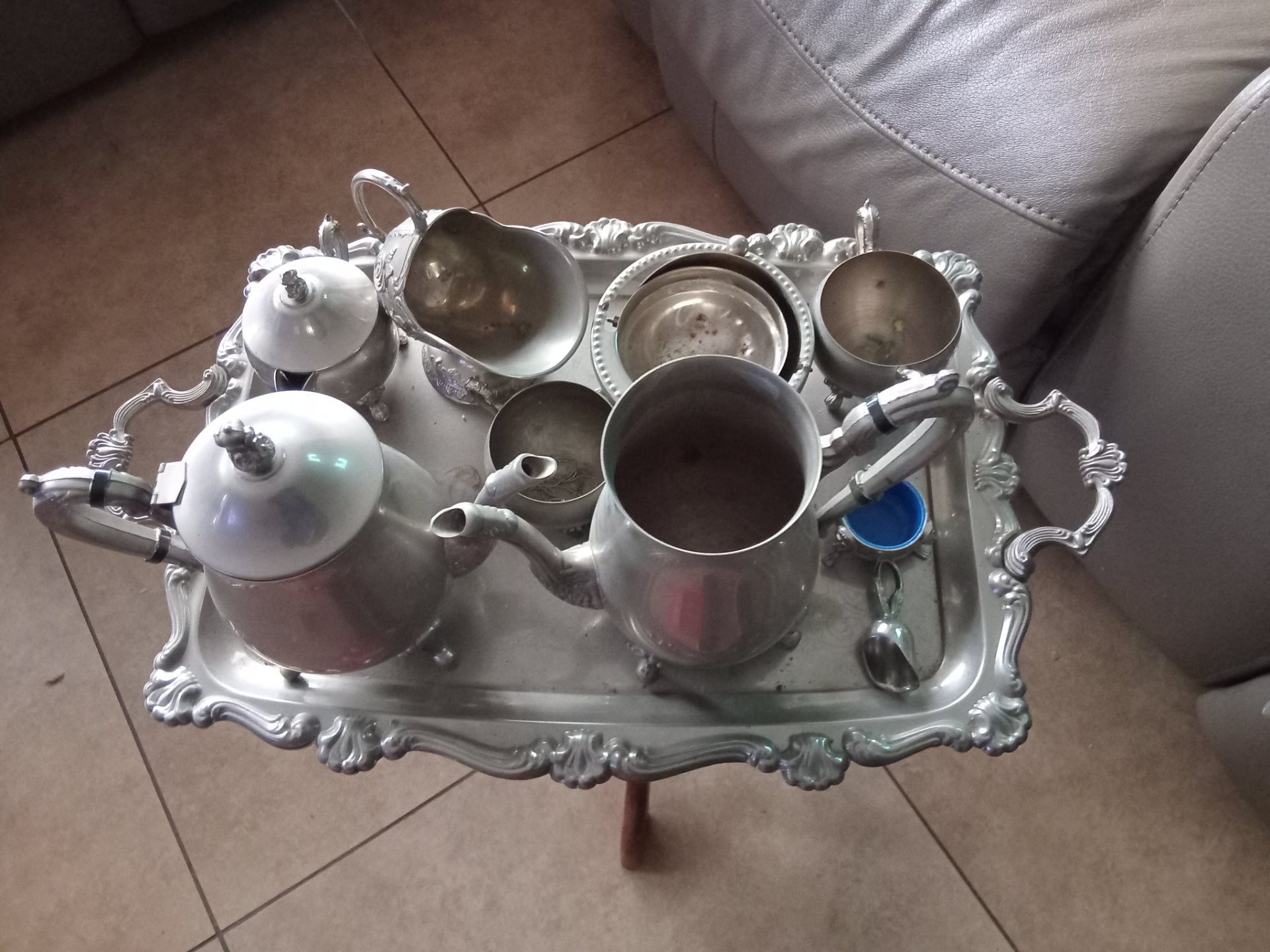 Assorted silver‑coloured tea & coffee service on ornate tray — mixed lot, used