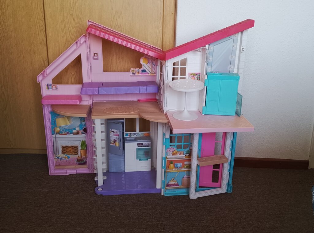 Large multi-level plastic dollhouse playset — colourful rooms, built-in kitchen decals, one round table included (used)