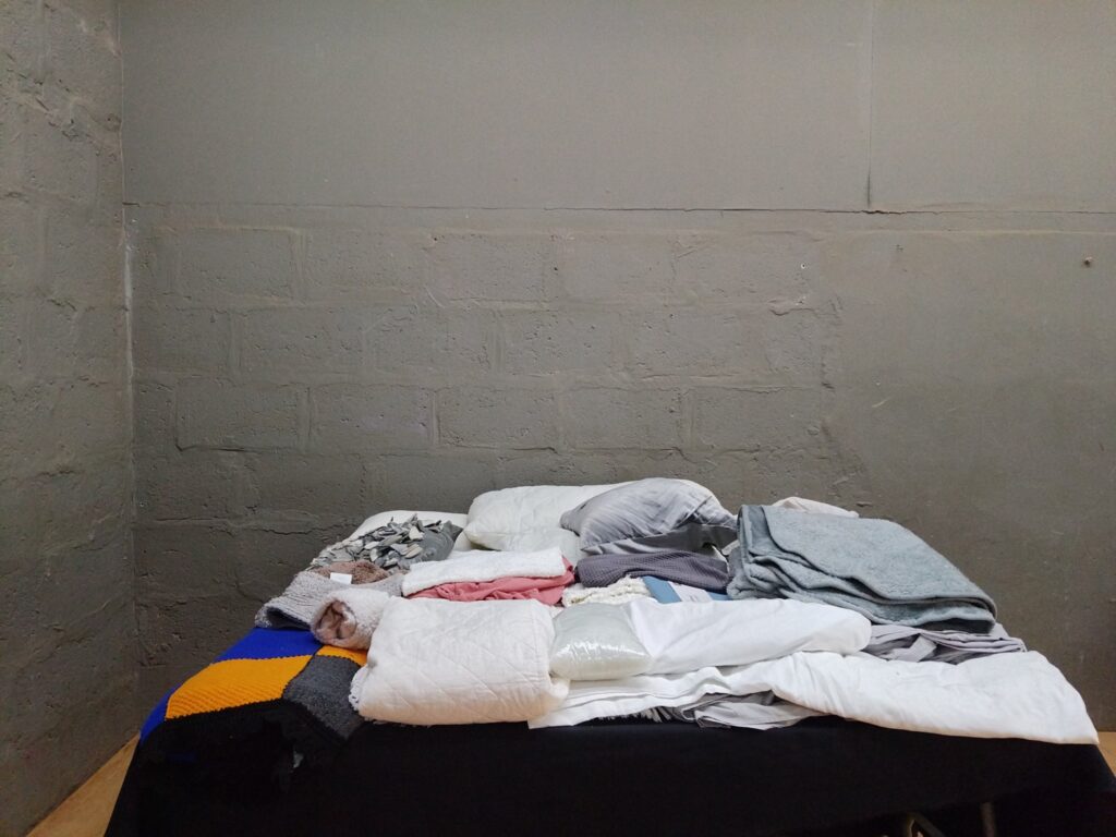 Assorted used bedding lot — pillows, cushion covers, throws and folded blankets