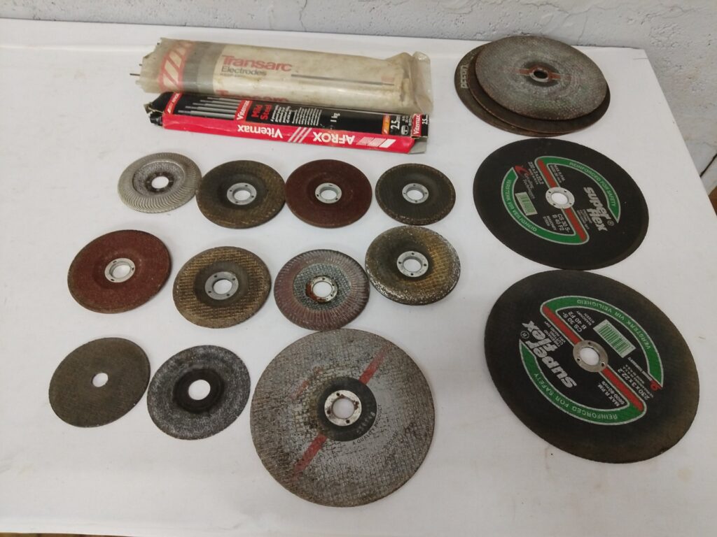 Assorted grinding, flap & cut‑off discs + welding electrodes — mixed lot (used, rusted, some broken)
