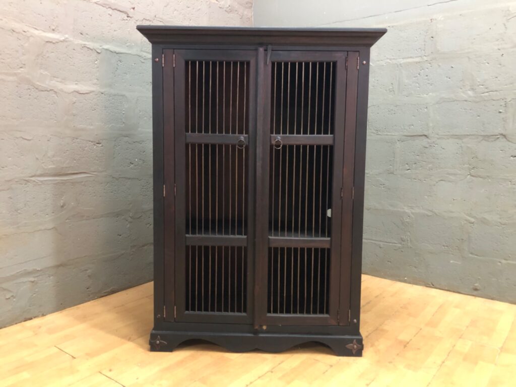 Tall dark-stained wooden freestanding cabinet — barred double doors, fixed shelves, cable hole